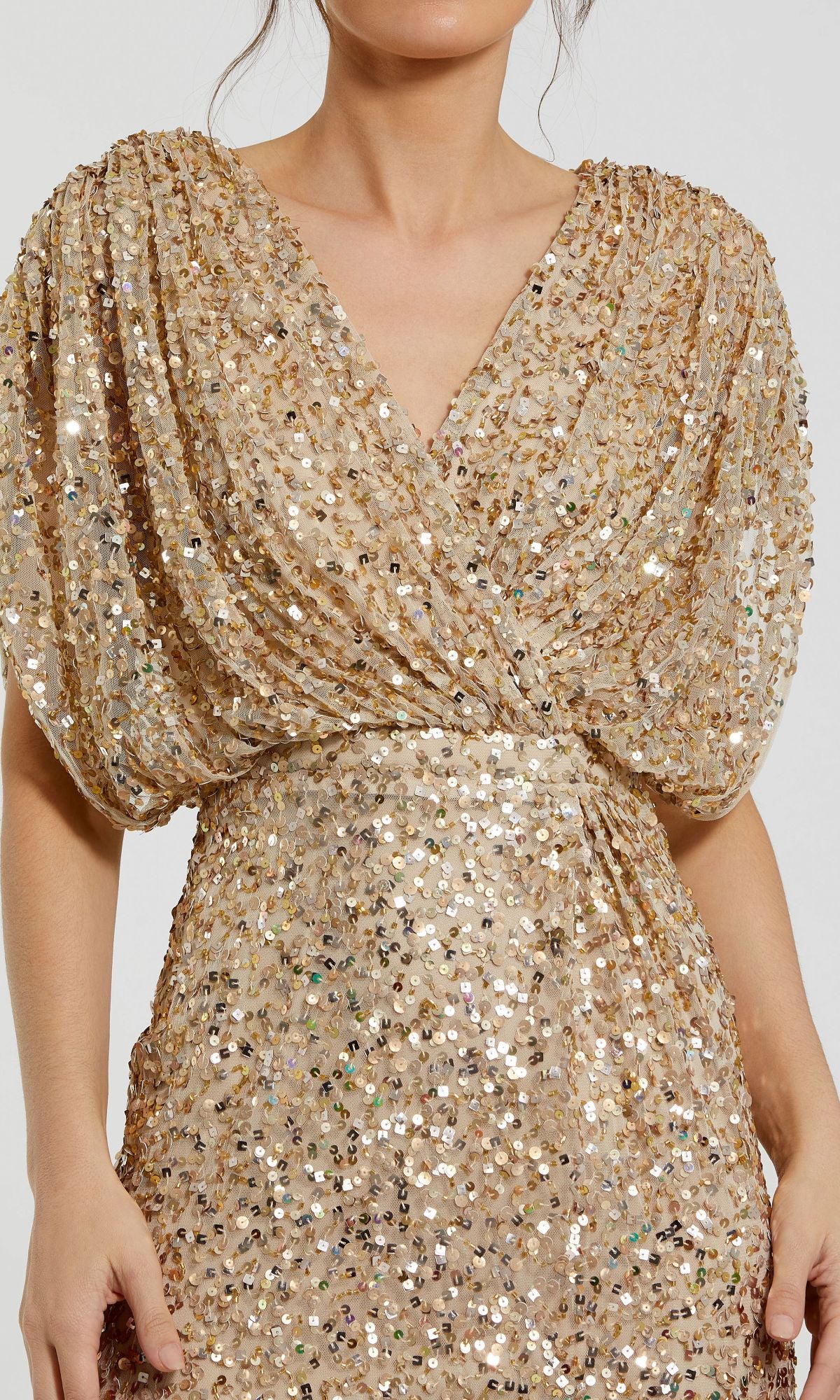 A person wearing the Mac Duggal 5640 Short Sleeve Long Sequin Formal Dress, featuring gold sequins, puff sleeves, and a V-neckline—an elegant choice for evening events.